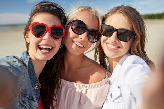 sommerferien, ferien, reisen und personenkonzept - gruppe lächelnder junger frauen, die selfie am strand machen