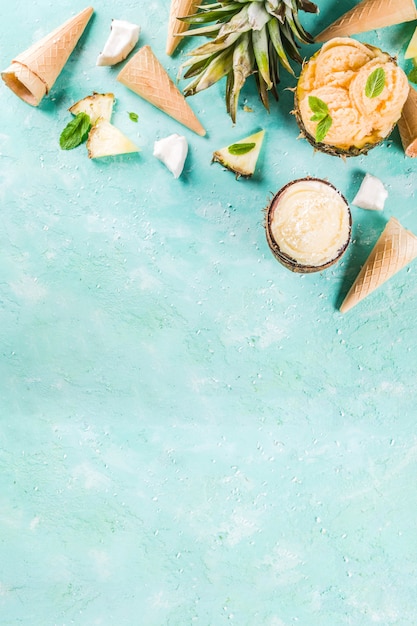 Sommerferien-Ferienkonzept, stellte verschiedene tropische Eissorbets, gefrorene Säfte in der Ananas, in der Pampelmuse und in der Kokosnuss, hellblaue konkrete Tabelle ein