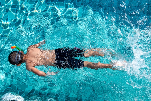 Sommerferien - glücklicher Junge in den Gesichtsmasken und in den Schnorcheln im Swimmingpool.