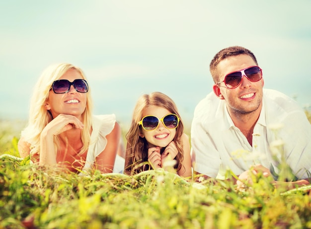 sommerferien, kinder- und menschenkonzept - glückliche familie mit blauem himmel und grünem gras