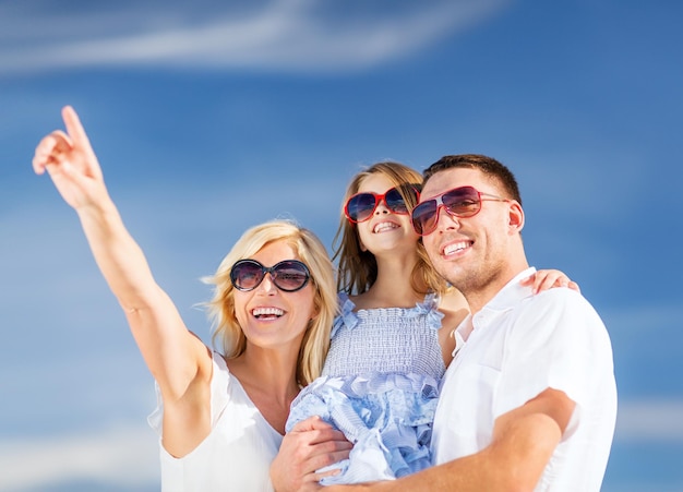 Sommerferien-, Kinder- und Menschenkonzept - glückliche Familie mit blauem Himmel