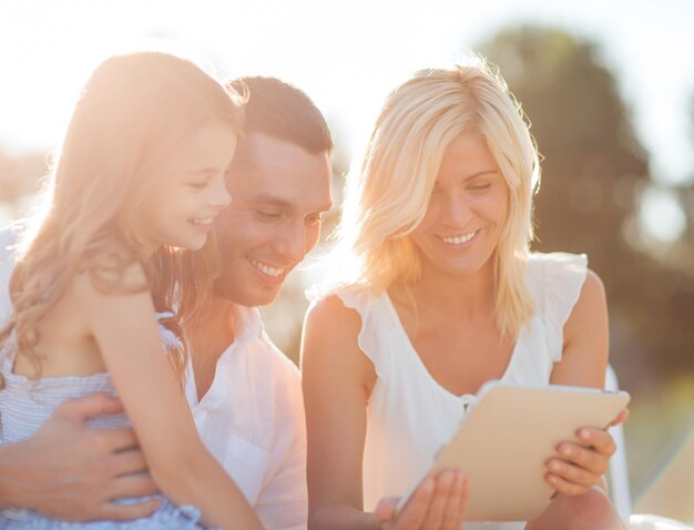 Sommerferien-, Kinder- und Menschenkonzept - glückliche Familie mit Tablet-PC unter Bild