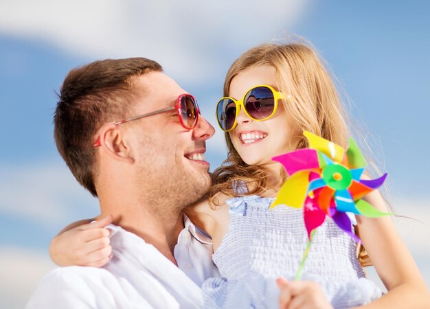 Sommerferien, Kinder- und Menschenkonzept - glücklicher Vater und Kind mit Sonnenbrille über blauem Himmel