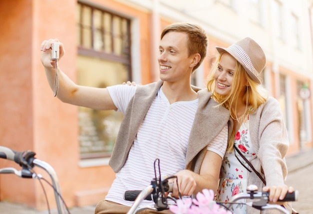 Sommerferien, Reisen, Urlaub, Tourismus und Dating-Konzept - reisendes Paar mit Fahrrädern, das ein Foto mit der Kamera macht