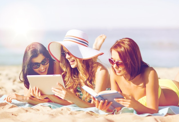 Sommerferien, Technologie und Internetkonzept - Mädchen in Bikinis mit Tablet-PC beim Sonnenbaden am Strand