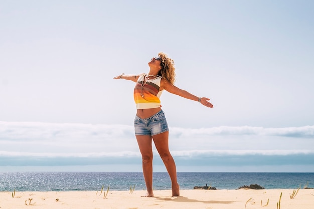 Sommerferien und Menschen reisen und das Strandkonzept mit schöner blonder Frau steht auf und offene Arme genießen Sonne und Saison