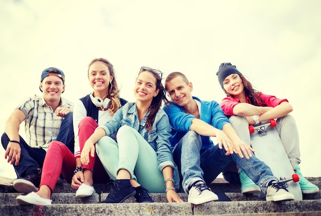 Foto sommerferien und teenagerkonzept - gruppe lächelnder jugendlicher, die draußen hängen