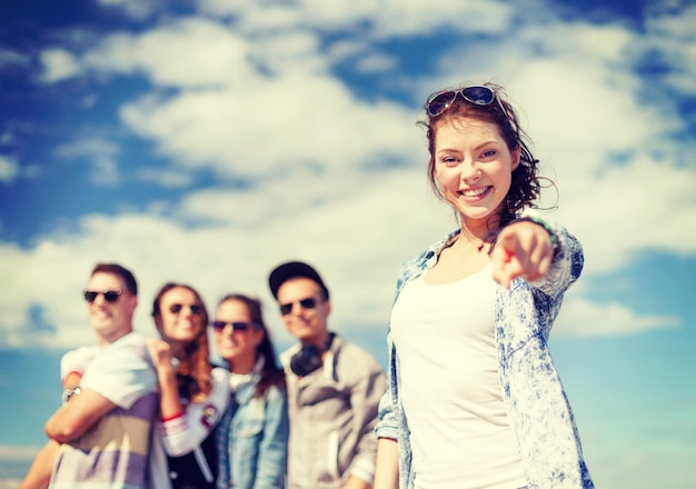 sommerferien und teenagerkonzept - teenagermädchen mit sonnenbrillen, die draußen mit freunden abhängen und daumen hoch zeigen