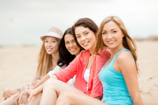 Sommerferien und Urlaubskonzept - lächelnde Mädchen mit Getränken am Strand