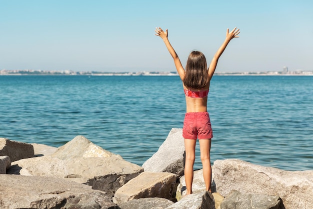 Sommerferien und Urlaubskonzept - Mädchen, das die Hände am Strand hält und die Meereslandschaft genießt