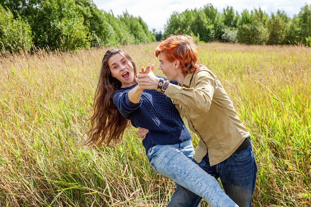 Sommerferien Urlaub glückliche Menschen Konzept. Liebespaar, das zusammen Spaß in der Natur im Freien hat. Glücklicher junger Mann, der mit seiner Freundin tanzt. Glückliches Liebespaar im Sommer im Freien.