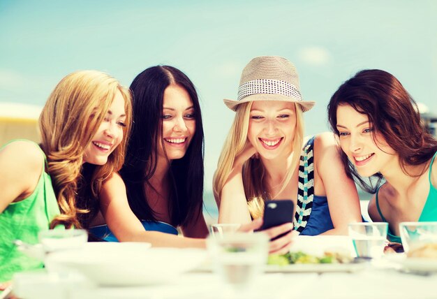sommerferien, urlaub und technik - mädchen, die im café am strand auf das smartphone schauen