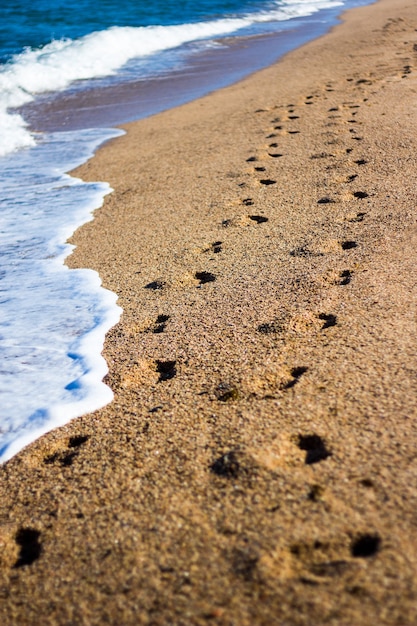 Sommerferienhintergrund - Fußabdrücke am Strand mit goldenem Sand