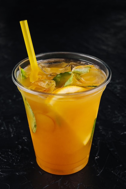 Sommerfrischer Cocktail mit Strohminze und Orangenstücken auf Schwarz