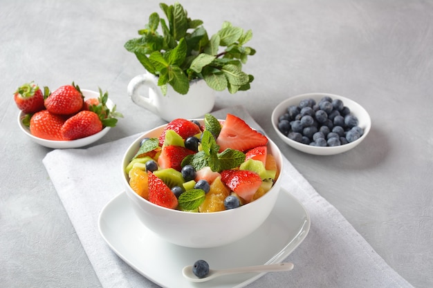 Sommerfruchtsalat mit Orangen, Erdbeeren, Blaubeeren, Kiwi und frischer Minze