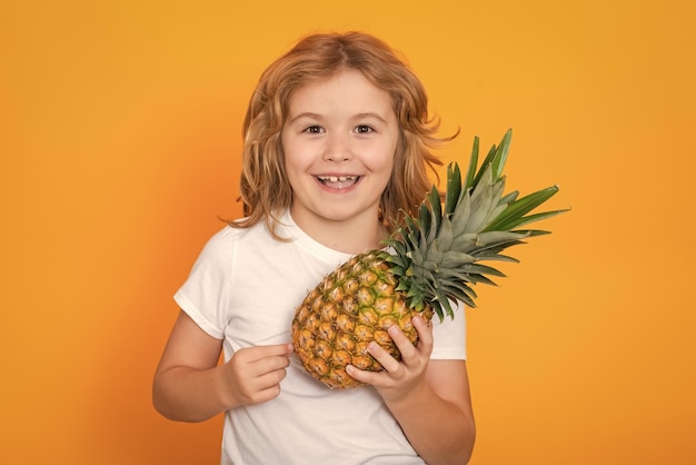 Sommerfrüchte Kind mit Ananas im Studio Studioporträt eines niedlichen Kindes hält Ananas isoliert auf gelbem Hintergrund