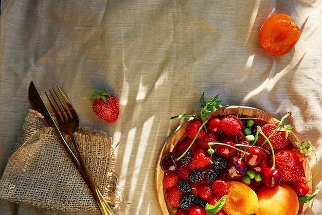 Sommerfrüchte und Beeren saisonaler Hintergrund unter harten Schatten Erdbeeren Aprikosen Kirsche Himbeere mit Besteck Gesunder Snack natürliches Dessert Vitamine Platz kopieren