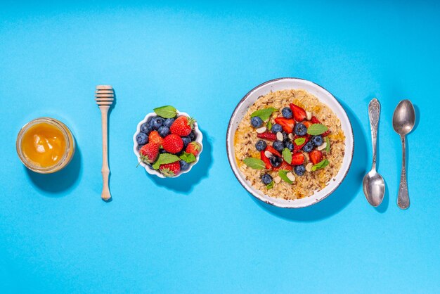 Sommerfrühstück Haferflocken mit Erdbeeren, Heidelbeeren, Nüssen, Schokolade und Honig, Draufsicht, Kopienraum, traditioneller Sommerfrucht- und Beerenhaferbrei