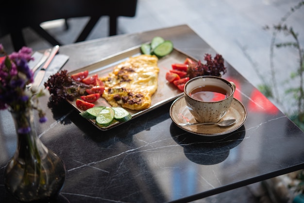 Sommerfrühstück im Cafe. Spiegeleier mit frischem Gemüse und einer Tasse Tee