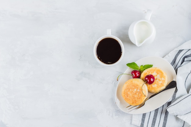 Sommerfrühstück mit Hüttenkäsepfannkuchen, Tasse schwarzen Kaffee, Milch