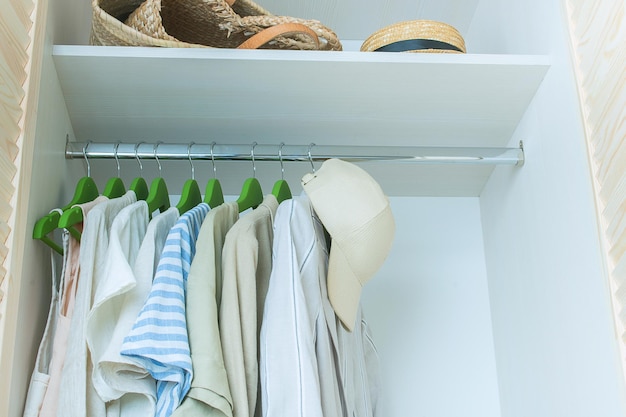 Sommergarderobe mit Leinenkleidung auf grünen Kleiderbügeln