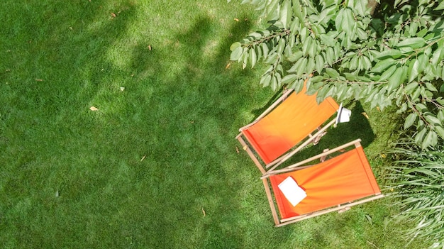 Sommergarten mit Sonnenliegen Liegestühle auf Gras Antenne Draufsicht grüne Parkbäume und Platz zum Entspannen