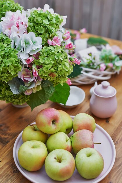 Sommergartenhintergrund. Blumenstrauß Hortensien und eine Tasse Tee auf dem Tisch. Guten gemütlichen Morgen. Picknick in der Natur. Grußkarte zum Muttertag. Feier