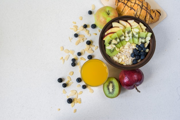 Sommergesundes Frühstück oder Snack. Haferflocken mit Beeren und Früchten, Saft und Krassan auf einem weißen flachen Tisch