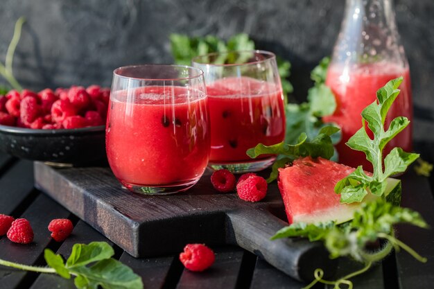 Sommergetränk Kalter Wassermelonensaft mit Limette und Minze auf einem Holzbrett