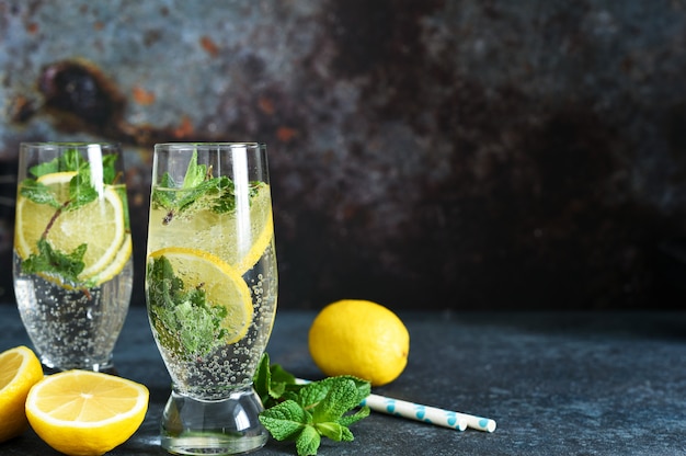 Sommergetränk mit Zitrone und Minze auf einem dunklen Tisch.