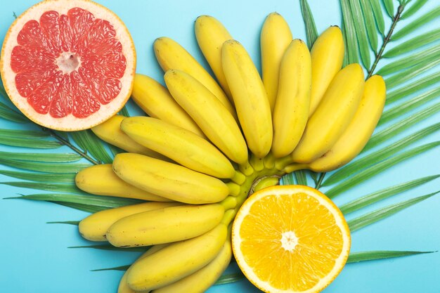 Sommerhintergrund der tropischen Früchte. Bananen, Orangen und Grapefruits auf einem farbigen blauen Hintergrund.