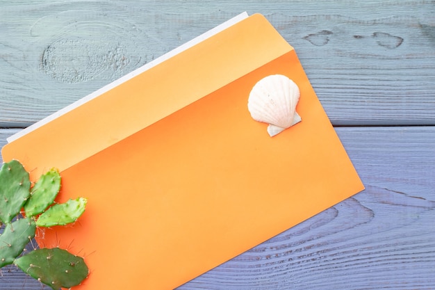 Sommerhintergrund orange Umschlag, saftig, Muschel auf blauem Holzhintergrund