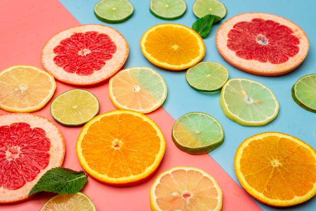 Sommerhintergrundkonzept geschnittene Orange, Grapefruit, Zitrone, Limette auf rosa und blauem Hintergrund