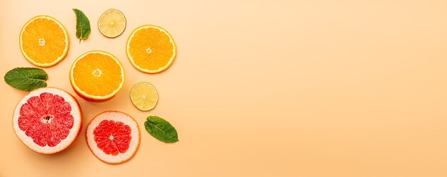 Sommerhintergrundkonzept geschnittene Orange, Grapefruit, Zitrone, Limette, Minze auf orangem Hintergrund