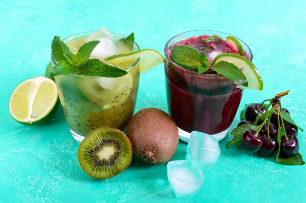 Sommerkalte Getränke mit frischem Obst, Beeren und Minze. Kirsch-Smoothies, Kiwi-Cocktail in Gläsern.