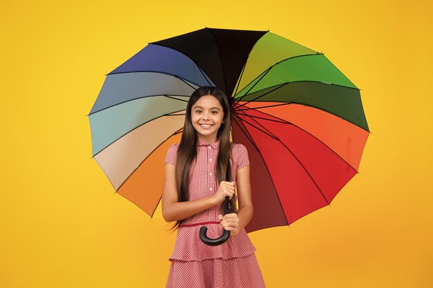 Sommerkleid Happy Teen Girl Holding Rainbow Umbella stehend isoliert auf gelbem Hintergrund isolated on white Fröhlich Teenager-Kind halten Sonnenschirm