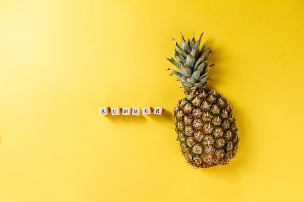 Sommerkonzept Konzeptionell Leckere appetitanregende Hälfte der Ananas auf gelb hellen lebendigen Hintergrund mit hölzernen Buchstaben. Flat Lay.