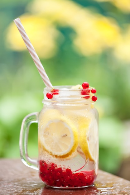 Sommerkühles Getränk zum Durstlöschen von Zitrone und Johannisbeere mit Eiswürfeln Sommerhintergrund