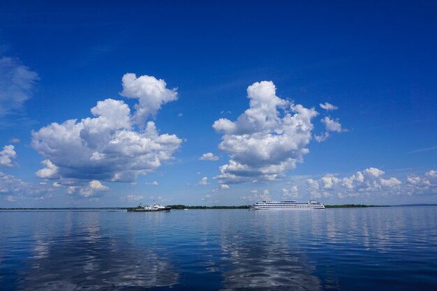 Sommerlandschaft am Fluss mit Wolken im blauen Himmel