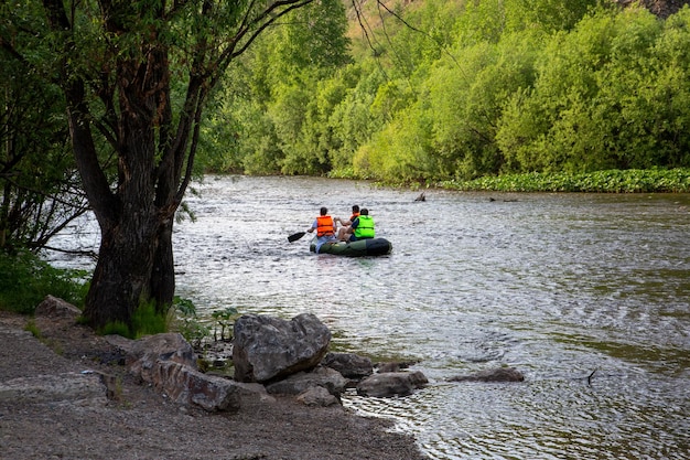 Sommerlandschaft ein Fluss mit grünen Ufern und einem Boot, das darauf schwimmt Aktive Erholung des Tourismus