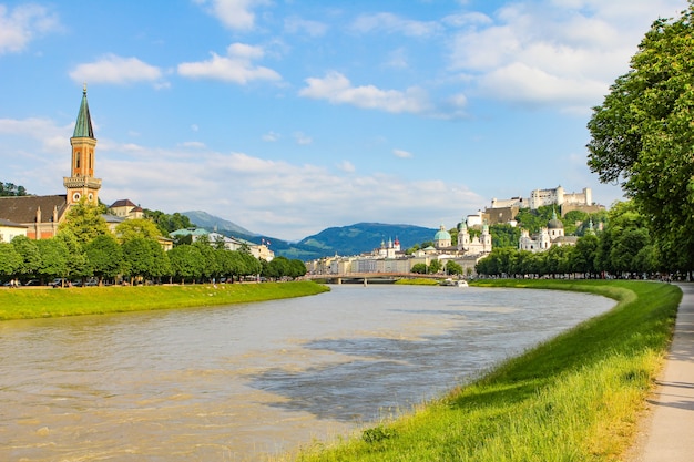 Sommerlandschaft einer europäischen Stadt. Gebirgsfluss, Berge, Kirche und Festung. Salzburg, Hohensalzburg