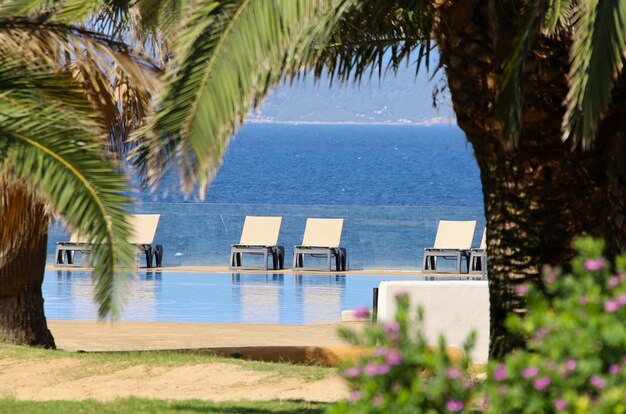 Foto sommerlandschaft mit liegestühlen, meer und swimmingpool.