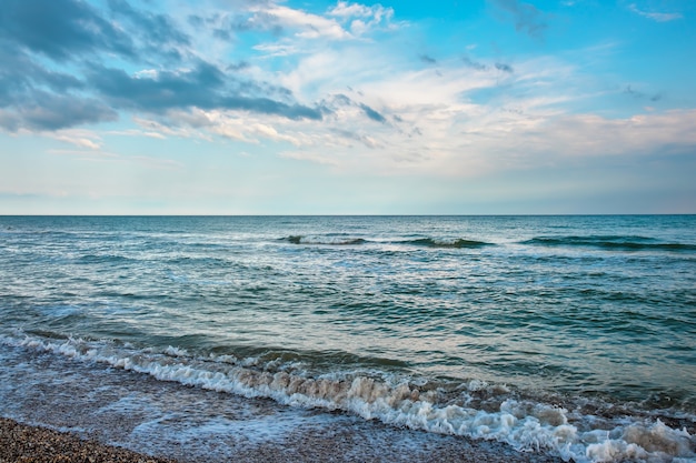 Sommerlandschaft mit Meer, Wellen, bewölkten Wolken.