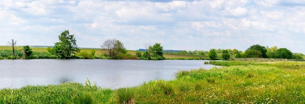 Sommerlandschaftspanorama mit Fluss und bewölktem Himmel