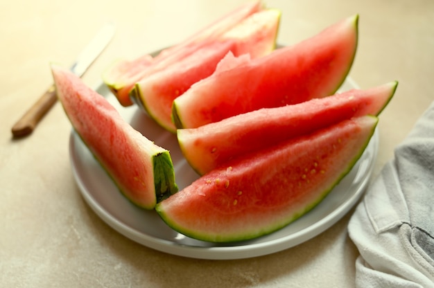 Sommerlebensmittelhintergrund. Reife Wassermelonenscheiben in einem Teller, auf warmem Hintergrund