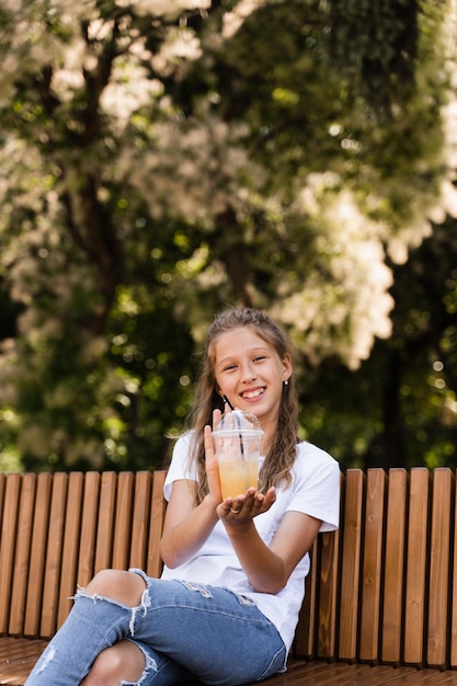 Sommerlimonadencocktail im Freien Glückliches Mädchen, das eine Tasse mit Orangenlimonade hält und lächelt und lacht