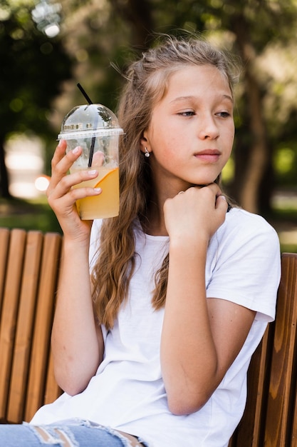 Sommerlimonadencocktail im Freien Glückliches Mädchen, das eine Tasse mit Orangenlimonade hält und lächelt und lacht