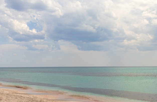 Sommermeer schön vom exotischen tropischen Strand. Smaragdgrün des Meeres und strahlend blauer Himmel mit Wolken mit Sonnenlicht. Sommermeerlandschaft, türkisfarbenes Meerwasser, Idyllinsel oder Strandbanner