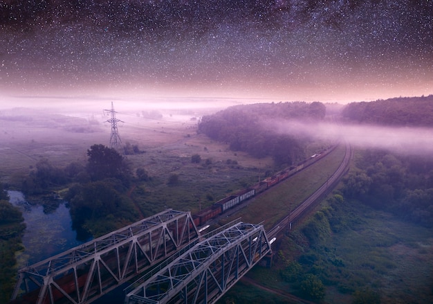 Sommernachtslandschaft, Eisenbahn durch den Wald. Sternenklarer Himmel.