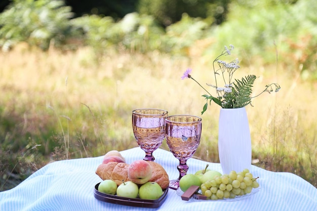 Sommerpicknick mit Croissants, Früchten, Schokolade und Gläsern Wein im Wald Cottage-Kernästhetik Sommerstimmung Kopierraum
